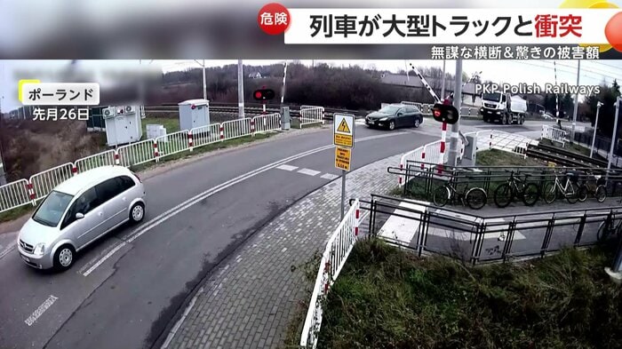 乗用車に続いて踏切に近づくトラック(PKP Polish Railways)