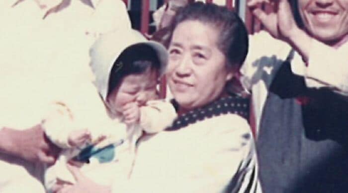 創業者・百代おばあちゃんに抱えられる大石社長（当時1歳）提供：テンホウ・フーズ