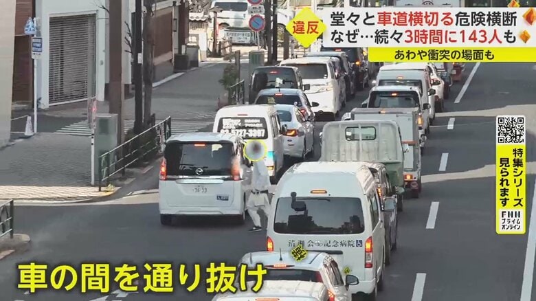 停車中の車の間を男性が渡っていく