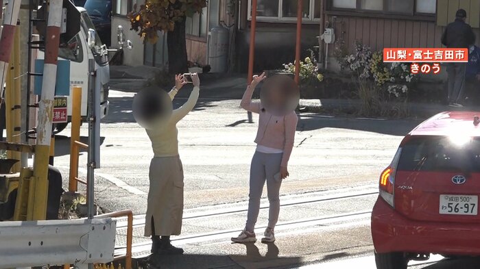 線路上でピースサインで撮影する観光客