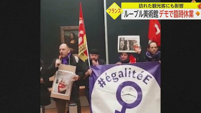モナリザの前で、スローガンの書かれた旗などを持ち叫ぶ人々(3月8日)