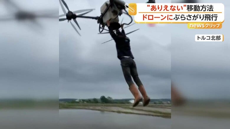 農業用ドローンにぶらさがり、田んぼの上空を飛ぶ男性（トルコ北部）