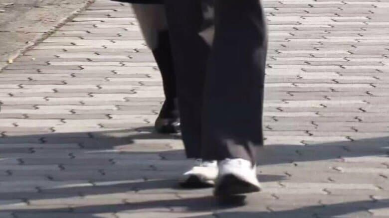 男子生徒の制服を着て裁判所に入る母親