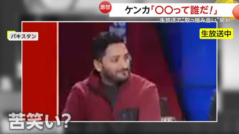2人の政治家のけんかをほほ笑みながら見ている赤い服の男性