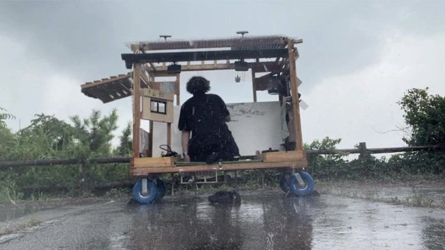雨の中、絵を描く土田
