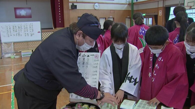 食品表示ラベルの貼り方を教わる児童たち