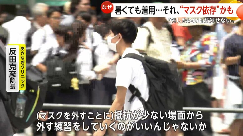 暑い中でもマスクを着用して歩く若者