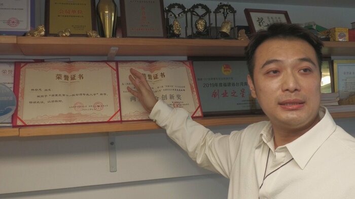 地元政府からの表彰状を説明する林さん