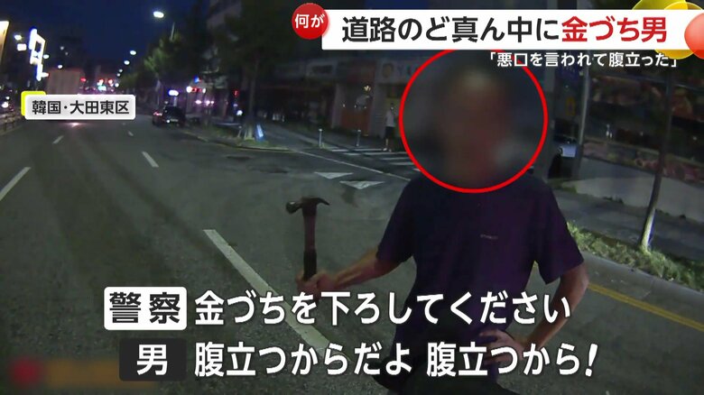 警察官とやり取りをする金づちを持った男