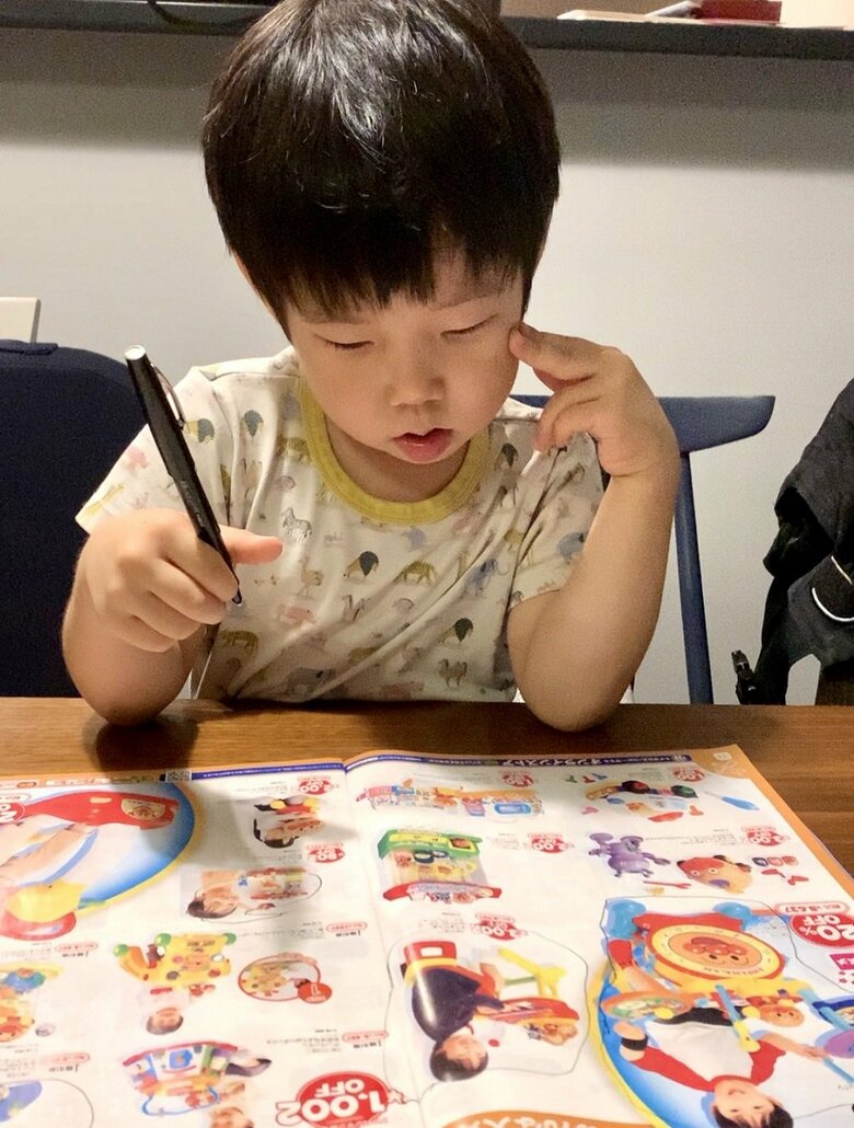 「う～ん…まいにち おかあちゃんたすけてあげてるからな～」とおもちゃのチラシをチェックする長男くん