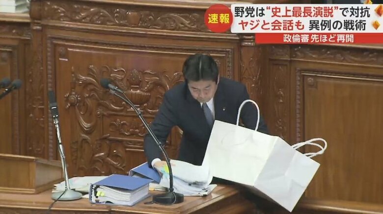大きな紙袋から大量の資料を取り出す立憲・山井議員