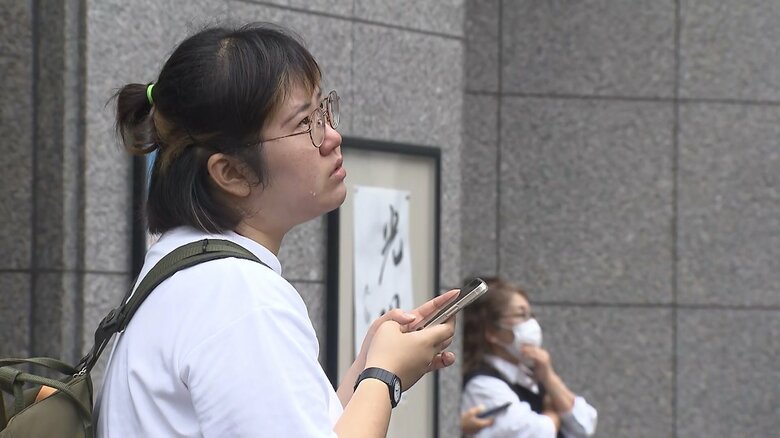 看板掛け替え作業を見つめる人たち