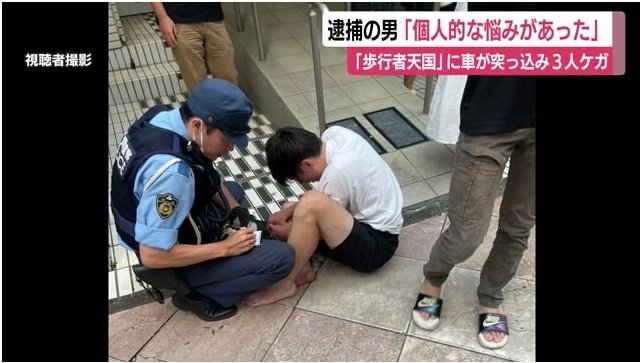 警察に事情を聞かれる男（8月11日）
