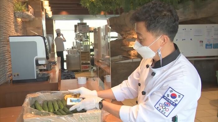 韓国の給食支援センタースタッフが日本産のキュウリに放射線測定器をかざしている
