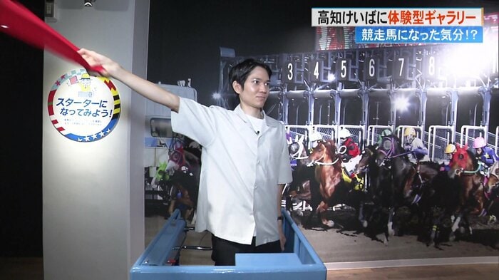 スターター台に立ち、旗を振る田村優介アナウンサー