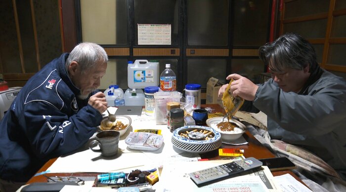 電子レンジで温めたレトルトカレーを食べる2人