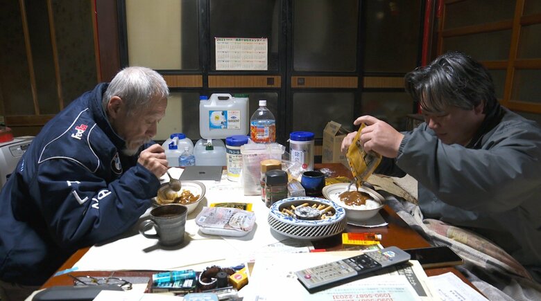 電子レンジで温めたレトルトカレーを食べる2人