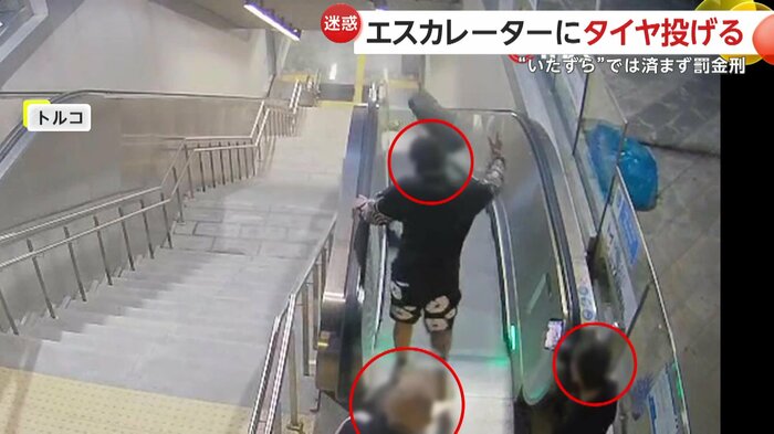 タイヤをエスカレーターの上から投げる若者