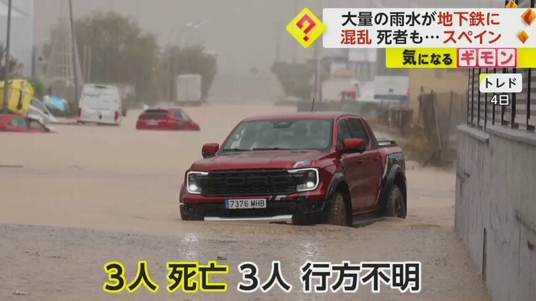 街の道路で洪水が起き、車体の半分が水に浸かっている車が見える