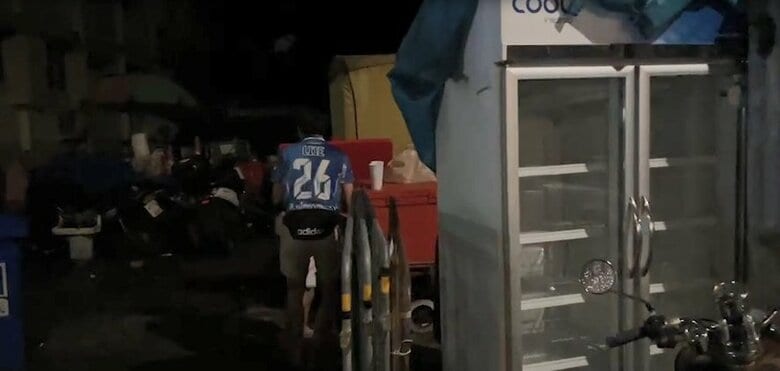 赤い大きなクーラーボックスの中で保管している酒を、白いカップへ注いでいく