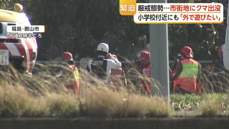 耳をふさぐ警察らの周りに白い煙が漂う