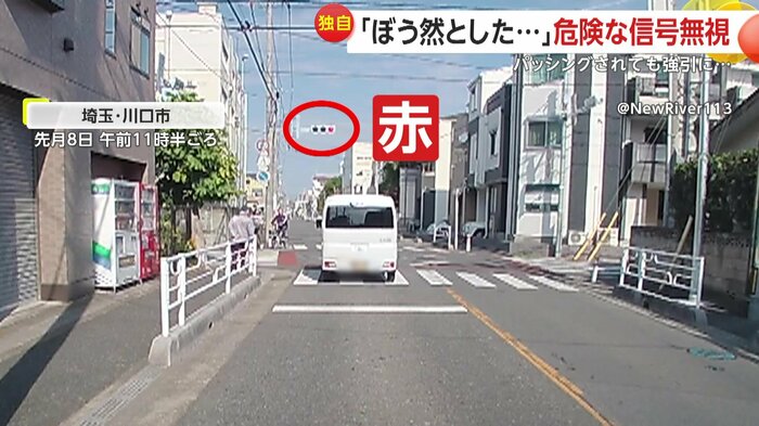 赤信号の交差点を真っ直ぐ進む白い車