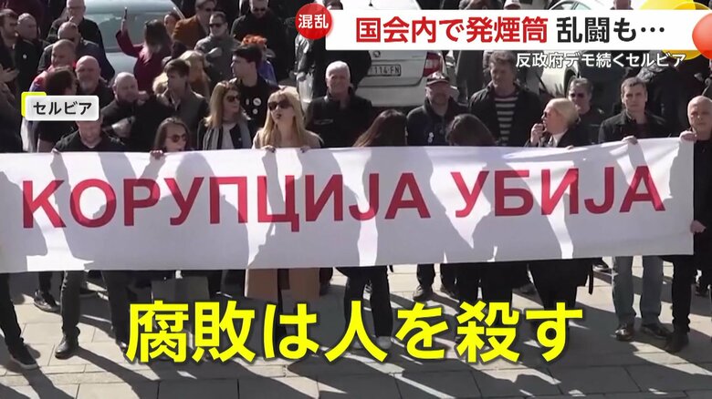 横断幕を掲げてデモを行う人々