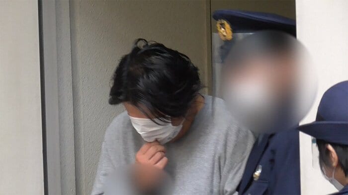 河合容疑者は、報道カメラを目にすると、サッとマスクを広げて、顔を隠した(7日 築地署)