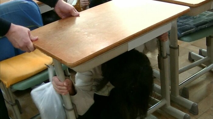 頭を守りながら机の脚をしっかり持つ