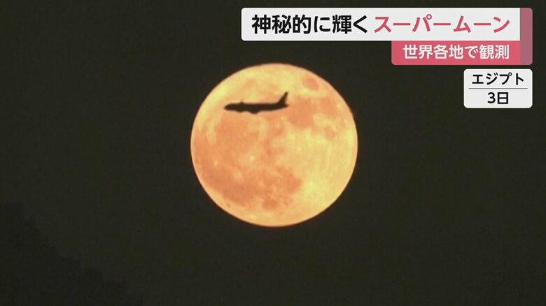 スーパームーンの前を旅客機が…