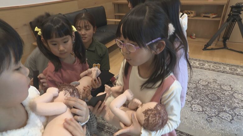 胎児の人形を抱っこする園児たち