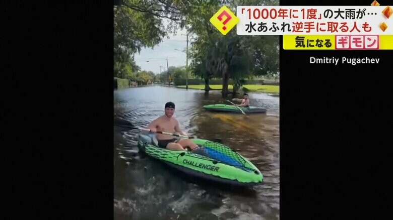 水没した道路で、ボートに乗る人たち