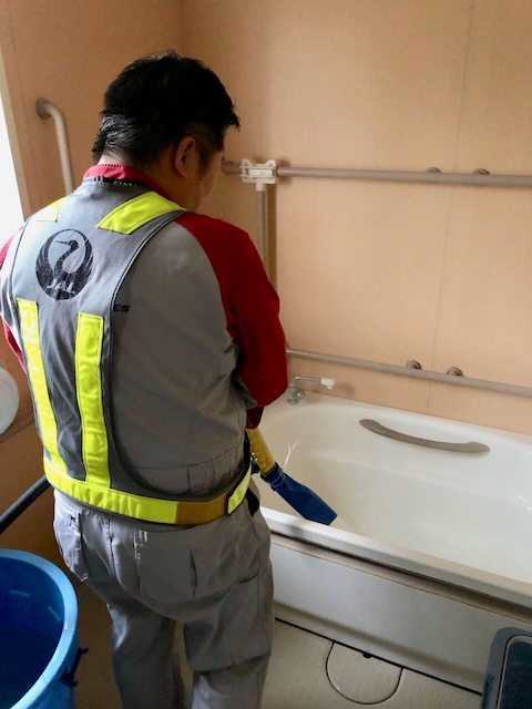 ホースを使い作業車からのお湯を入れるスタッフ(13日、多古町)