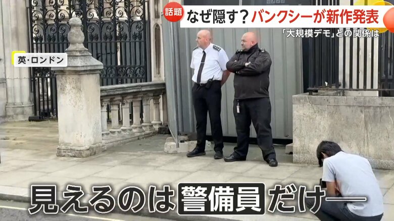 作品の前に立てられたバリケードの前に立つ屈強な警備員