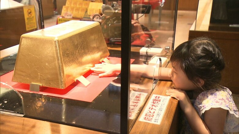 巨大金塊に触れる子供