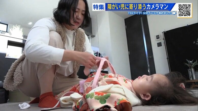 障がい児の体勢に合わせて着付けをする榎さん
