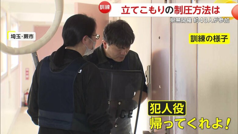 部屋に立てこもる犯人役と交渉を続ける警察官