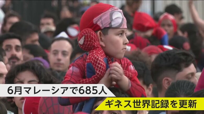 肩車されながら、スパイダーマンの人形を持つ子ども