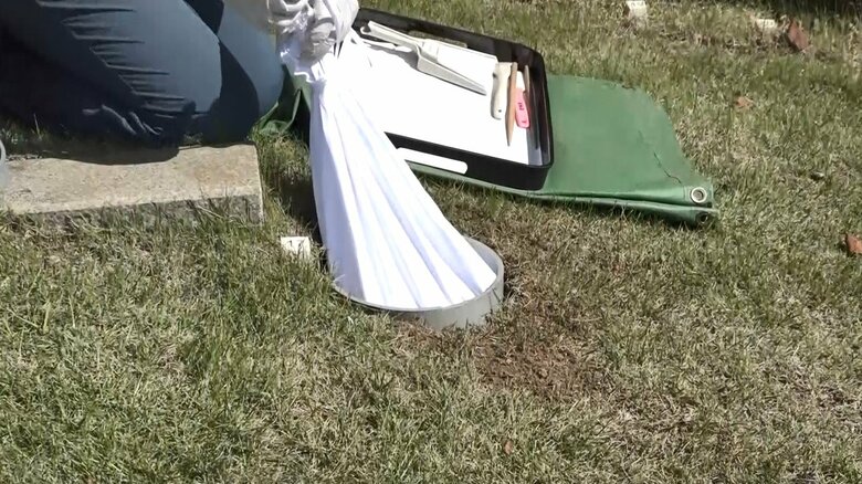 遺骨の入った袋を地面の穴の中へ（※骨の代替品を使用）