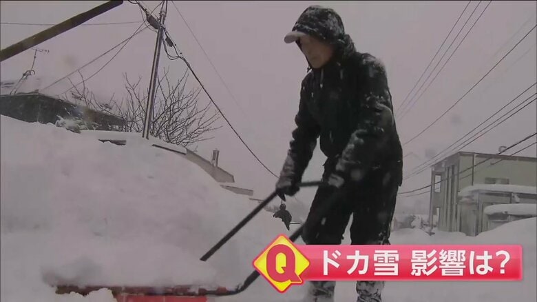 降り続く雪の中で雪かきをする人