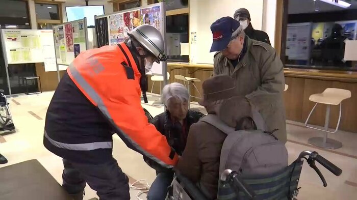 夜間避難訓練で車いすを使う人たちを誘導する田中さん