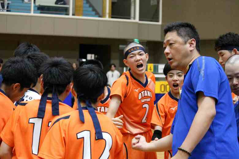 平本和久監督（左）と円陣を組む選手たち