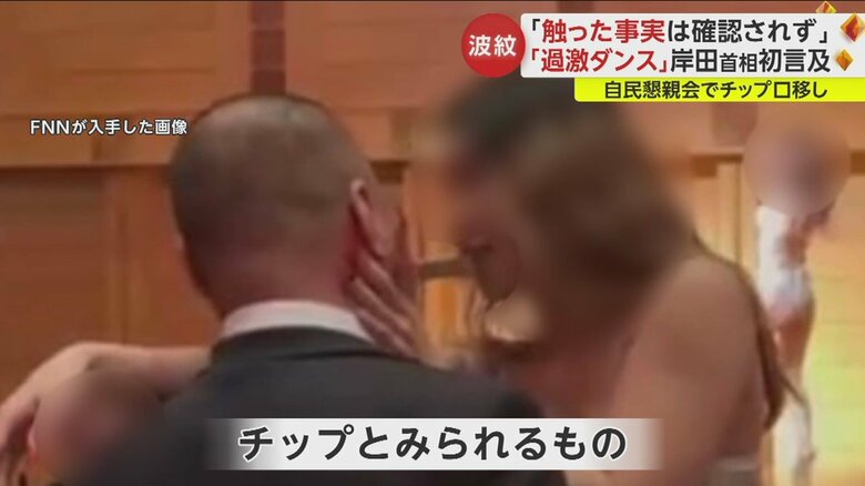 女性ダンサーとスーツ姿の男性が密着し、チップとみられるものをお互いにくわえている