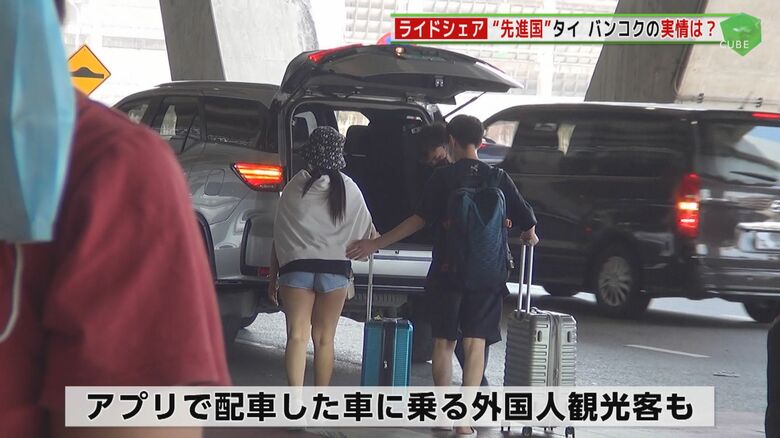 アプリで配車した車に乗り込む外国人観光客