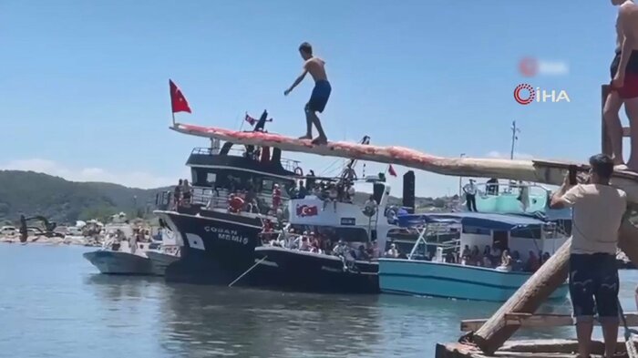海の上に突き出した棒の上を渡る男性