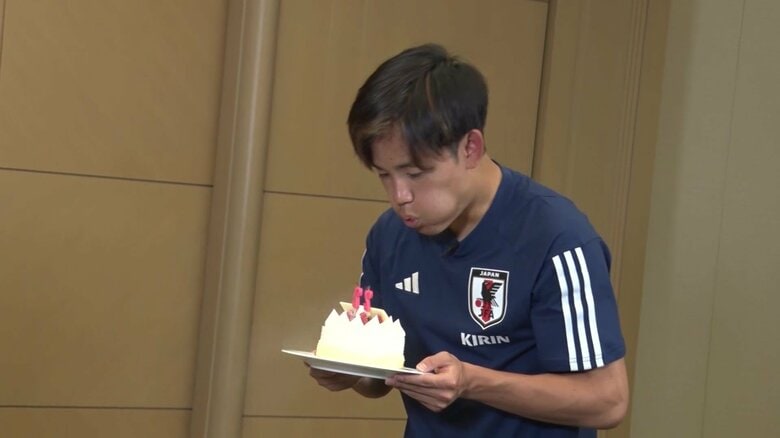 誕生日ケーキのろうそくを吹き消す久保。