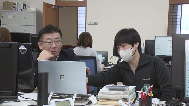 職員たちと並んで仕事をする佐藤町長（左）