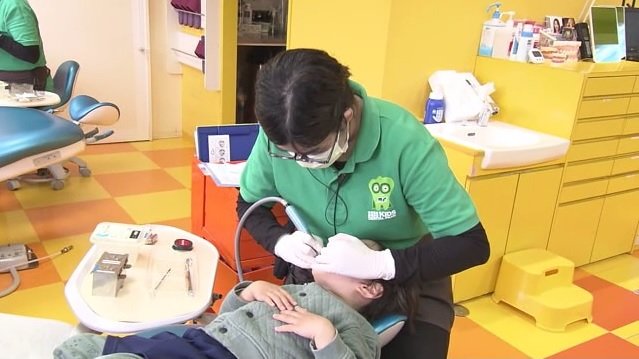 子供の口をみながら保護者にアドバイスする歯科衛生士