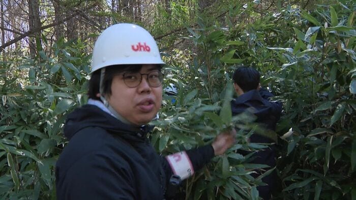 道警の指導のもと笹やぶに入る川瀬雄也記者
