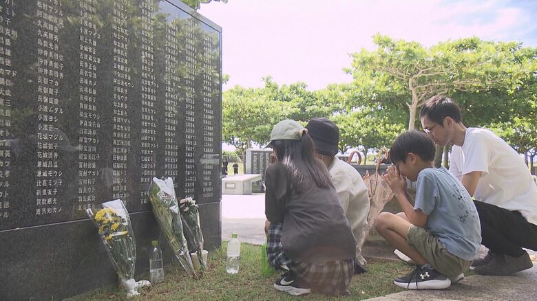 慰霊碑の前で手を合わせる人々